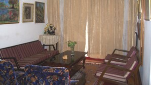 A living room with a sofa, chairs, a coffee table, and a painting on the wall. - Blue Chip Guest House Kolkata (Kolkata)
