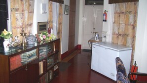 A room with a wooden desk, books, a small plant, and a white appliance. - Blue Chip Guest House Kolkata (Kolkata)