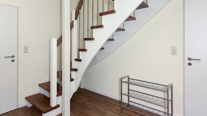 Una escalera con peldaños de madera y paredes blancas que conduce a una puerta.