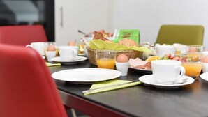 Una mesa de desayuno servida con platos, tazas y una cesta de comida.