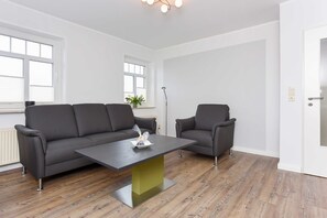 Uma sala de estar moderna com um sofá cinzento, uma poltrona a combinar e uma mesa de centro.