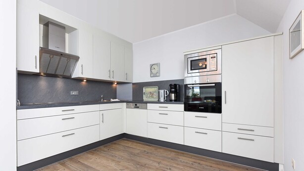 Cocina moderna con armarios blancos, microondas y cafetera.