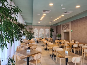 A spacious restaurant with wooden tables and chairs, ceiling lights, and decorative wall panels. - Nessebar Beach Hotel (Nessebar)
