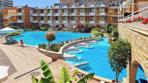 Un hôtel doté d’une piscine, de plusieurs balcons et offrant une vue sur les bâtiments environnants.