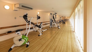Une salle de sport équipée de machines de cardio, de matériel de musculation et dotée d’un plancher en bois.