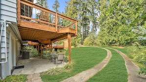 A wooden deck with a table and chairs, surrounded by a well-maintained lawn and tall trees. - Long Term Stay Discount. Business, Couples and Families Welcome/Ground Floor (Bothell)