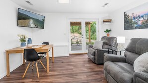 A modern living room with a wooden dining table, black chairs, a grey sofa, and a flat-screen TV on the wall. - Long Term Stay Discount. Business, Couples and Families Welcome/Ground Floor (Bothell)