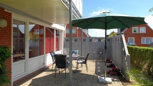 A patio with outdoor furniture, a table, and chairs, surrounded by a brick wall and a hedge. - Apartment "top right" - House Pamir (Neuharlingersiel)