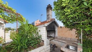A small outdoor kitchen with a stone chimney, a sink, and a fire pit. - Amazing apartment in Okrug Donji with WiFi (Okrug Donji)