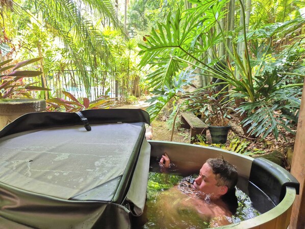 A man in a hot tub surrounded by lush greenery.