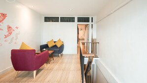 Ein modernes Wohnzimmer mit einem roten Sessel, einem blauen Sofa mit gelben Kissen und einem Holztisch.