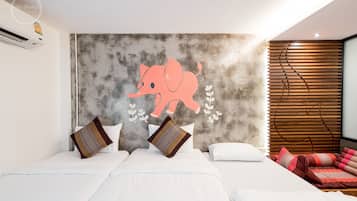 A hotel room with a large elephant mural on the wall, a bed with white linens, and a wooden slatted headboard.