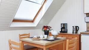 Ein Essbereich mit Tisch, Stühlen, einer Kaffeemaschine und einem Wasserkocher.