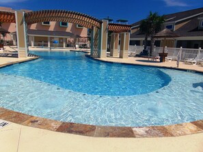 A swimming pool with a 10-foot entry, surrounded by lounge chairs and a covered seating area. - 1b/1b for 6 max4adults! Heated pools! Steps from the BEACH! Netflix! Playground! (Corpus Christi)