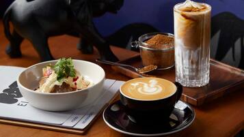 Una mesa con un plato de comida, una taza de café y un vaso de café helado.