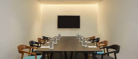 A conference room with a long table, chairs, a flat-screen TV, and water bottles.