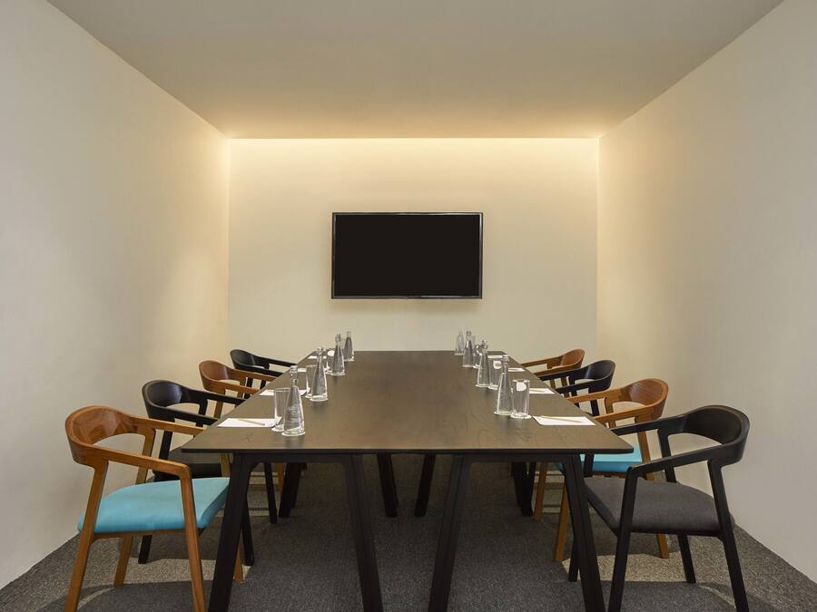 A conference room with a long table, chairs, a flat-screen TV, and water bottles.
