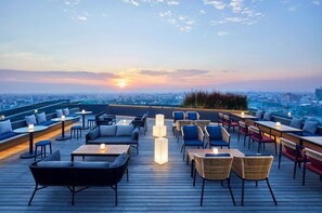 A rooftop terrace with seating areas, tables, and a view of the cityscape during sunset. - ARTOTEL Gajahmada Semarang (Semarang)