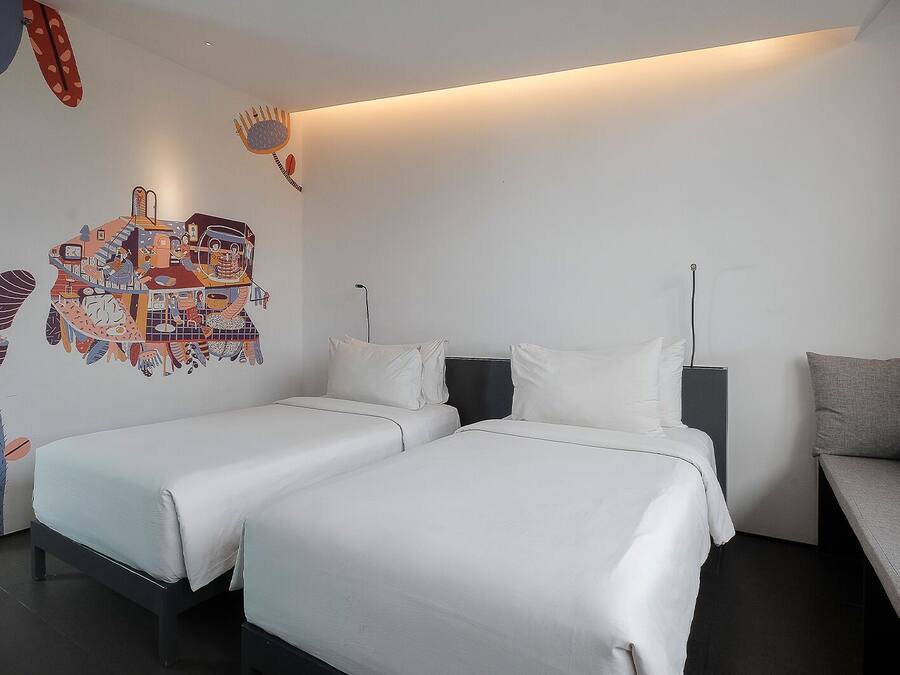 Habitación de hotel con dos camas, un sofá y un mural en la pared.