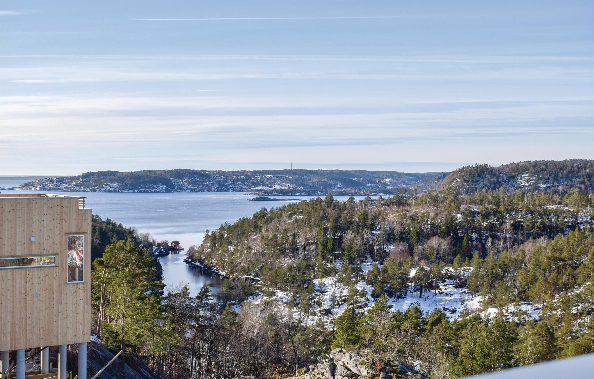 A modern building with a view of a lake and forested hills.