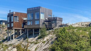 Un immeuble moderne à plusieurs étages, doté d’une façade en bois, de grandes fenêtres et d’un balcon.