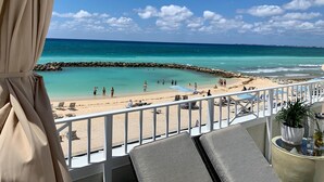 Ein Balkon mit Blick auf einen Strand, Liegestühlen und einem Geländer.