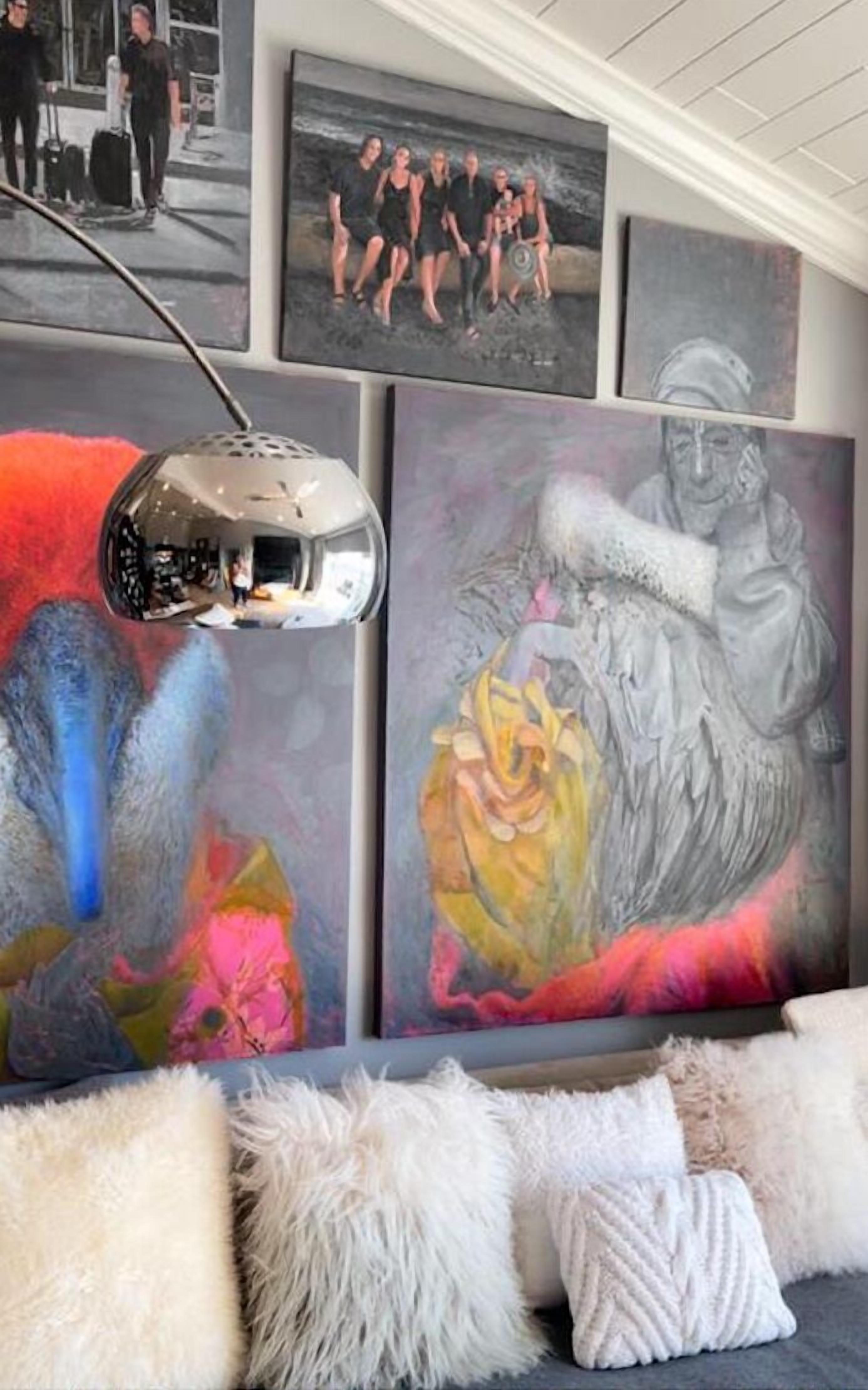 Ein Zimmer mit abstrakten Gemälden an der Wand, einer Lampe und flauschigen weißen Kissen.