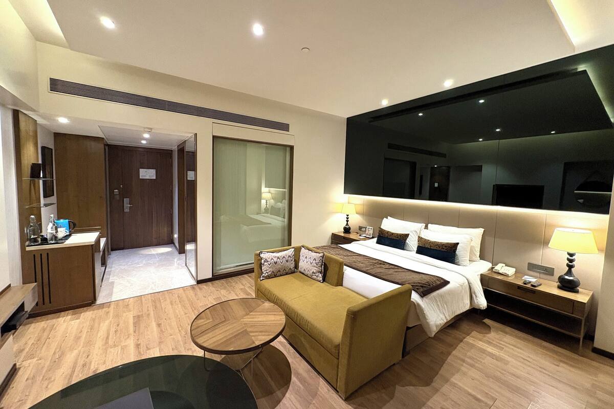 A modern hotel room with a bed, a sofa, a coffee table, and a desk.