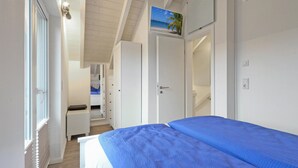 A bedroom with a bed, a wardrobe, a desk, and a view of the sea through a window. - Beautiful home in Süssau/Ostsee (Süssau/Ostsee)