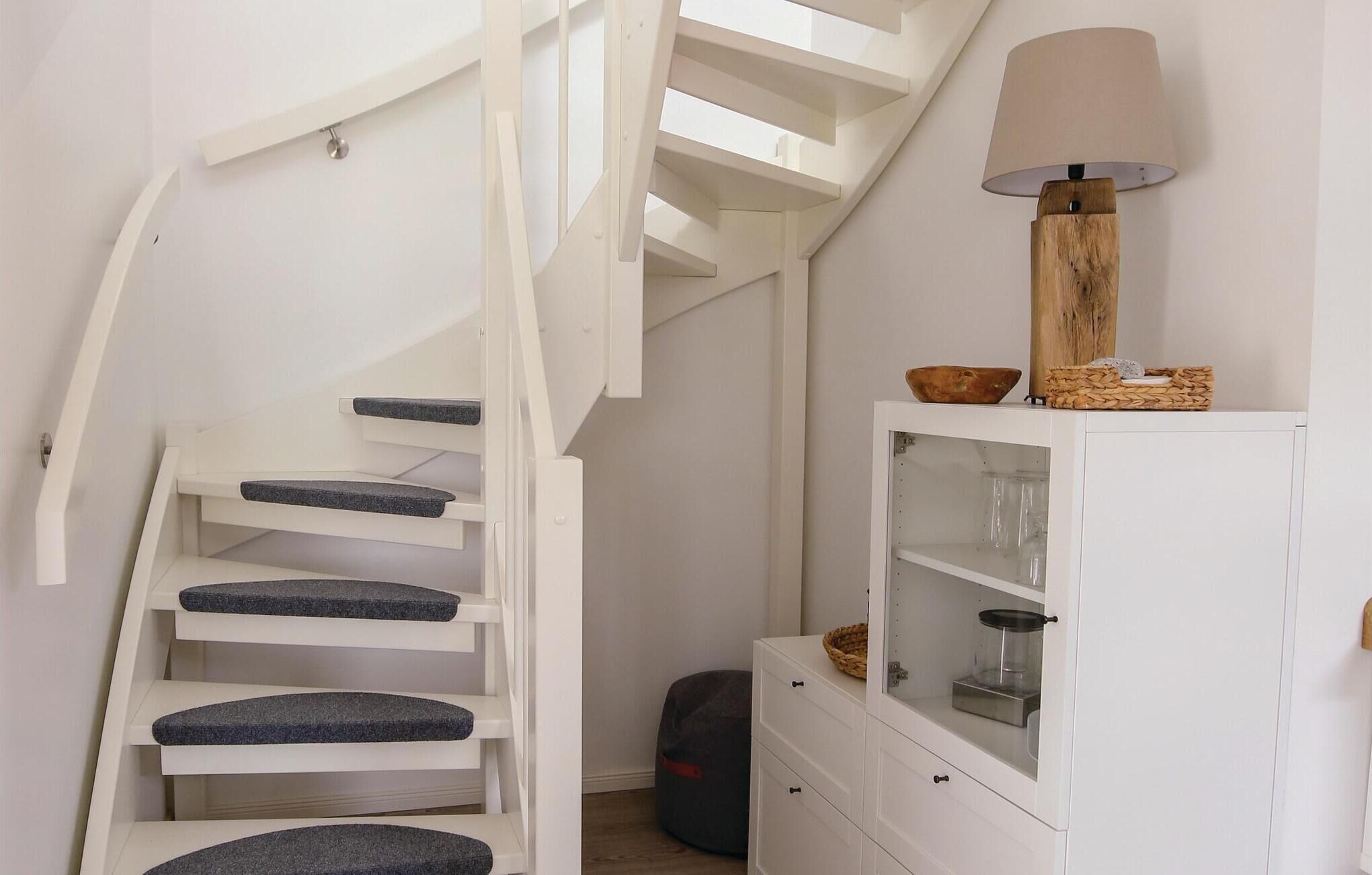 Een witte trap met blauwe treden en een houten lamp bovenop.