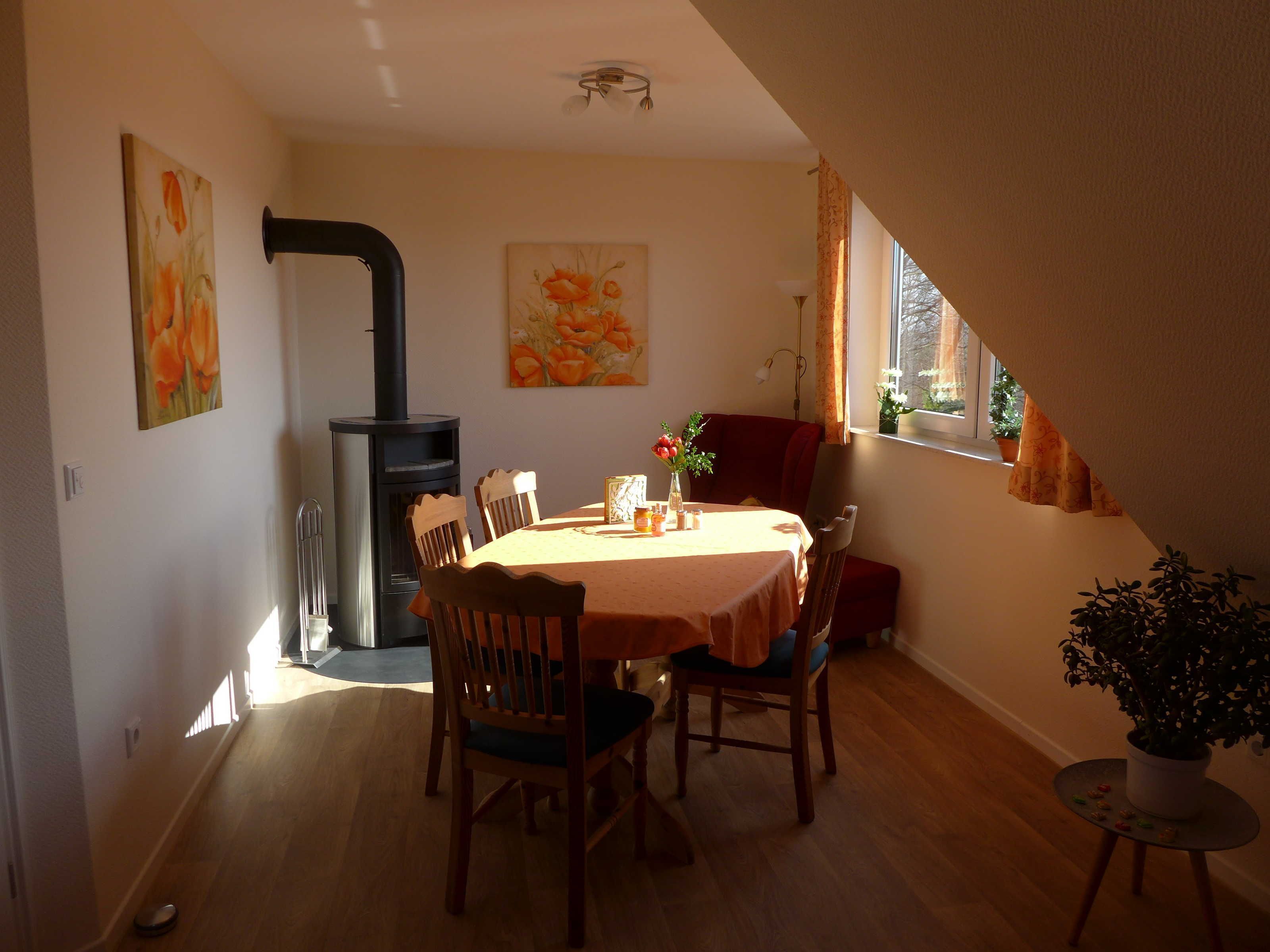 Un comedor con una mesa, sillas, chimenea y ventana con cortinas.