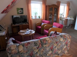 Un salon comprenant un téléviseur, deux canapés, une table à manger et un meuble.