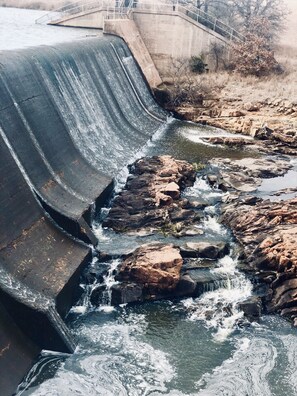 Una presa de hormigón con agua cayendo en cascada sobre rocas.