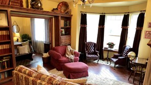 A cozy living room with a sofa, armchair, and a wooden coffee table. There is a bookshelf filled with books and a globe on a side table.