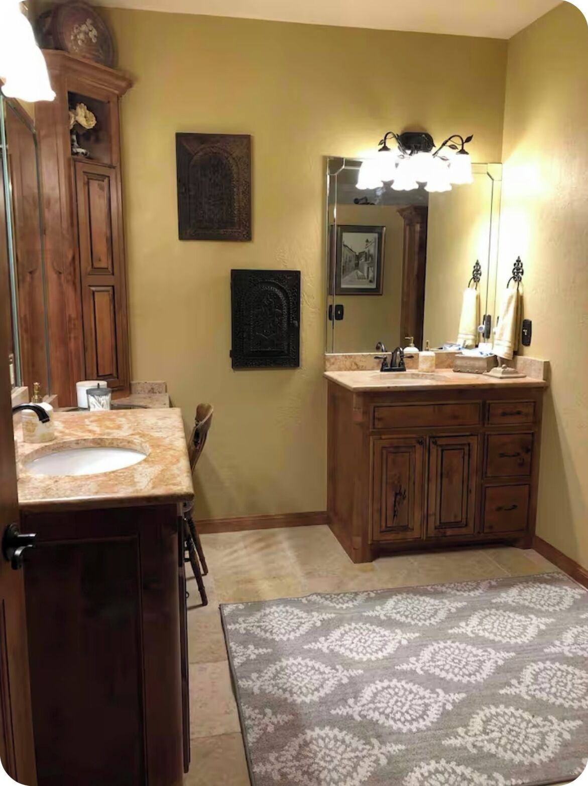 A bathroom with a wooden vanity, a sink, a mirror, and a patterned rug.