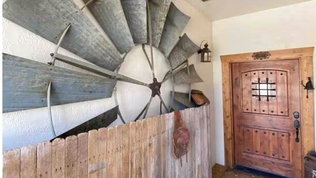 A spiral staircase with a rustic design, a wooden door with a grid pattern, and a wooden floor.