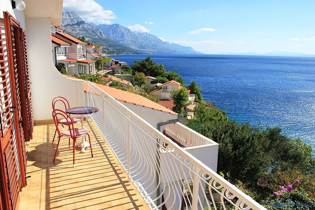 A balcony with a view of the sea and mountains.