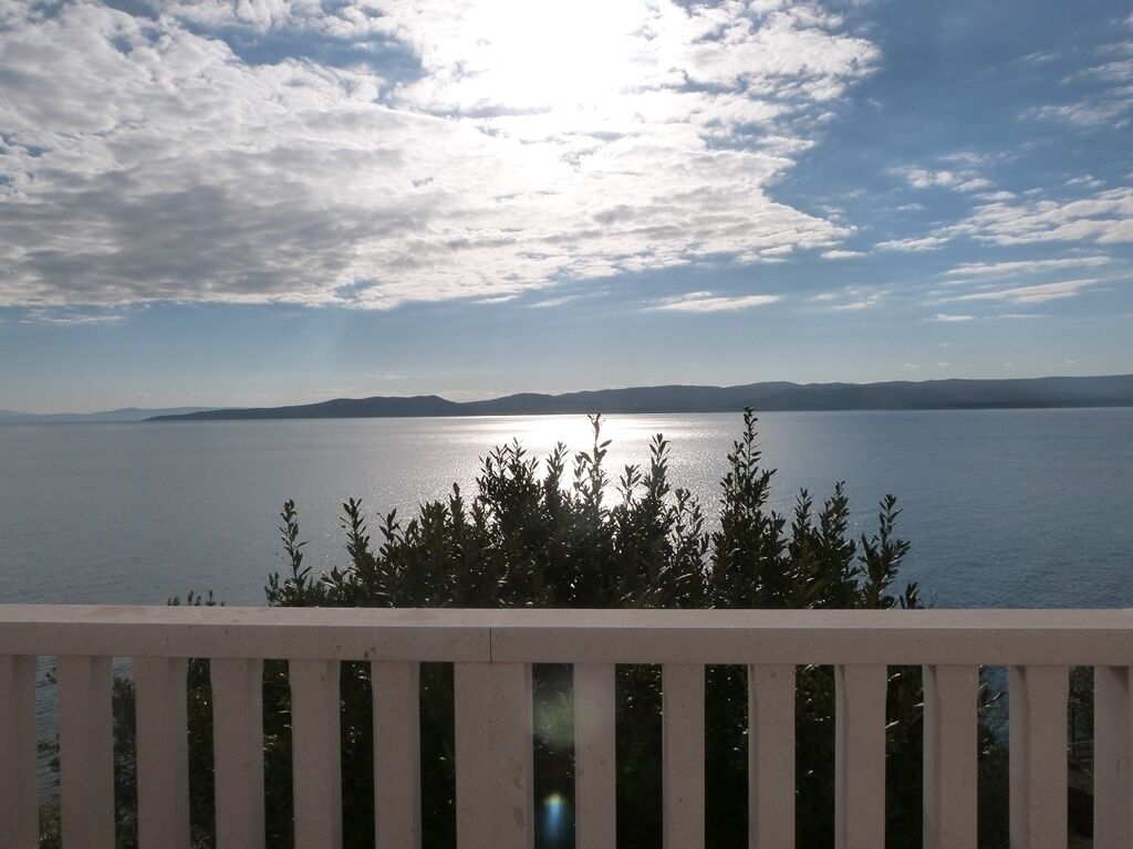 Vista de águas calmas com terras distantes sob um céu parcialmente nublado.