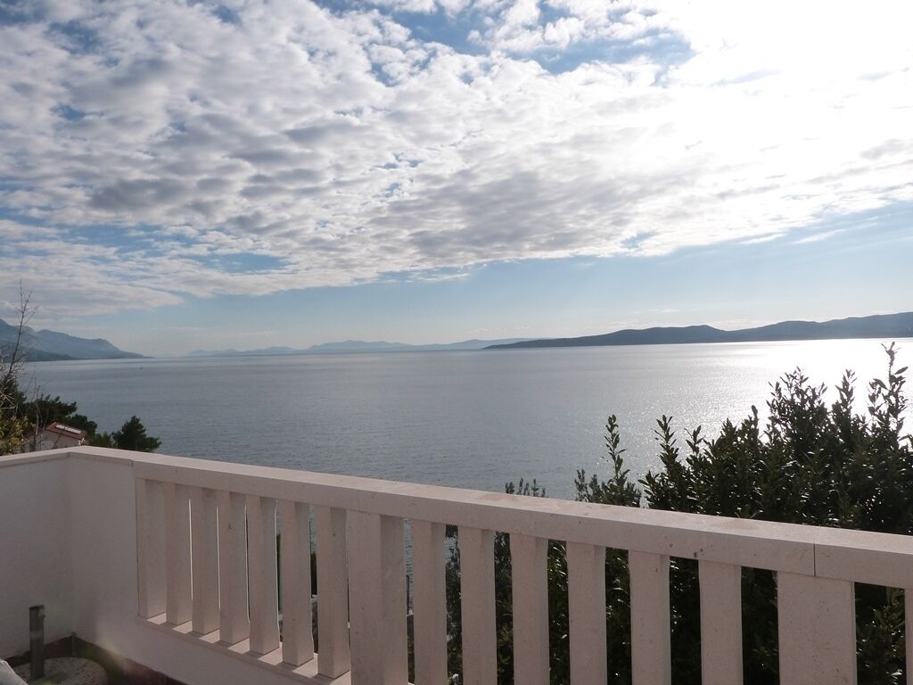 A balcony with a view of a large body of water and distant mountains under a partly cloudy sky.