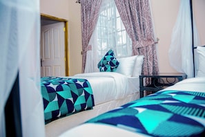 A bedroom with two beds, a nightstand, and a window with curtains. - Zakinn Hotel Gangilonga Iringa (Iringa)