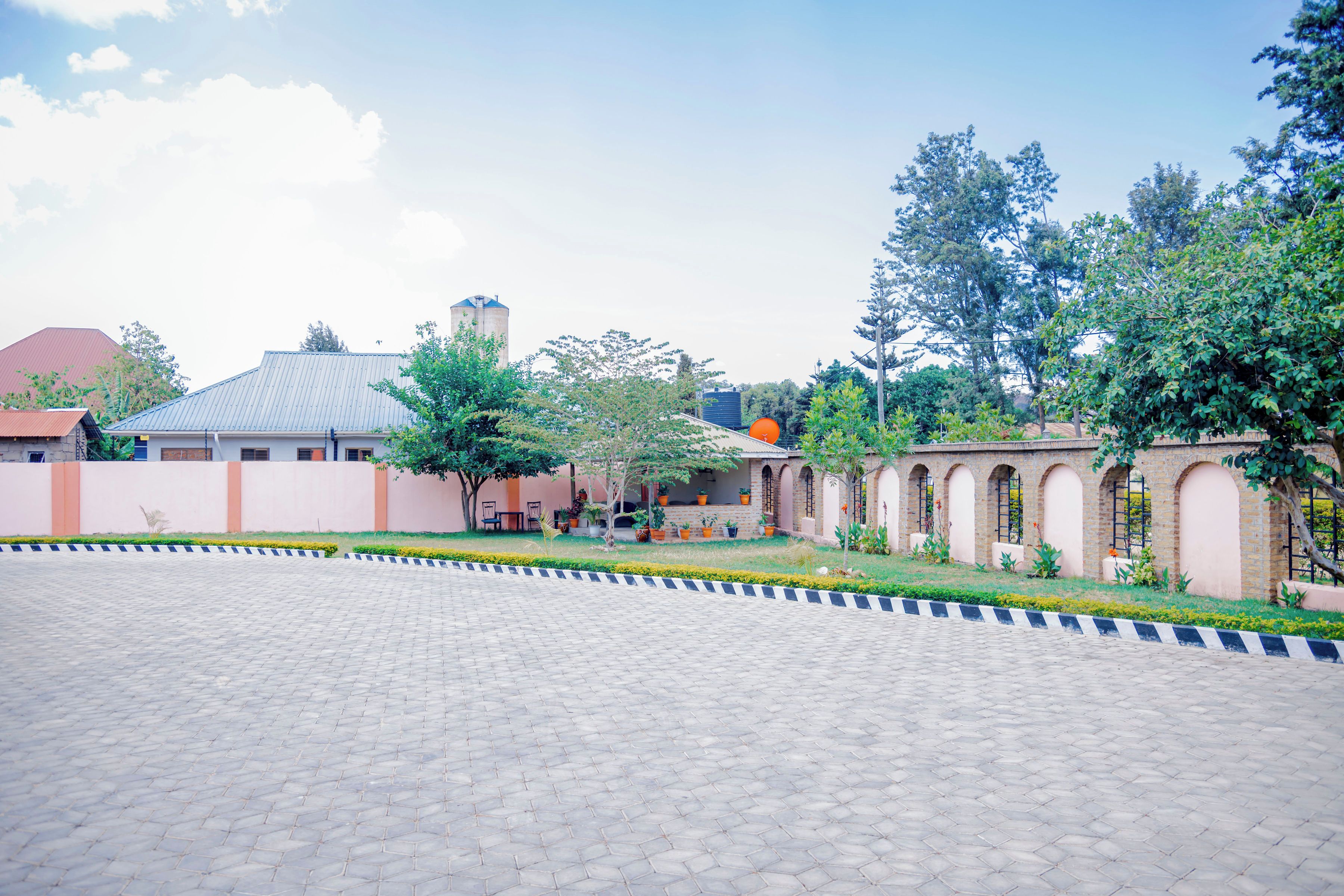 A courtyard with a paved walkway, a brick building with arches, and a water tower.