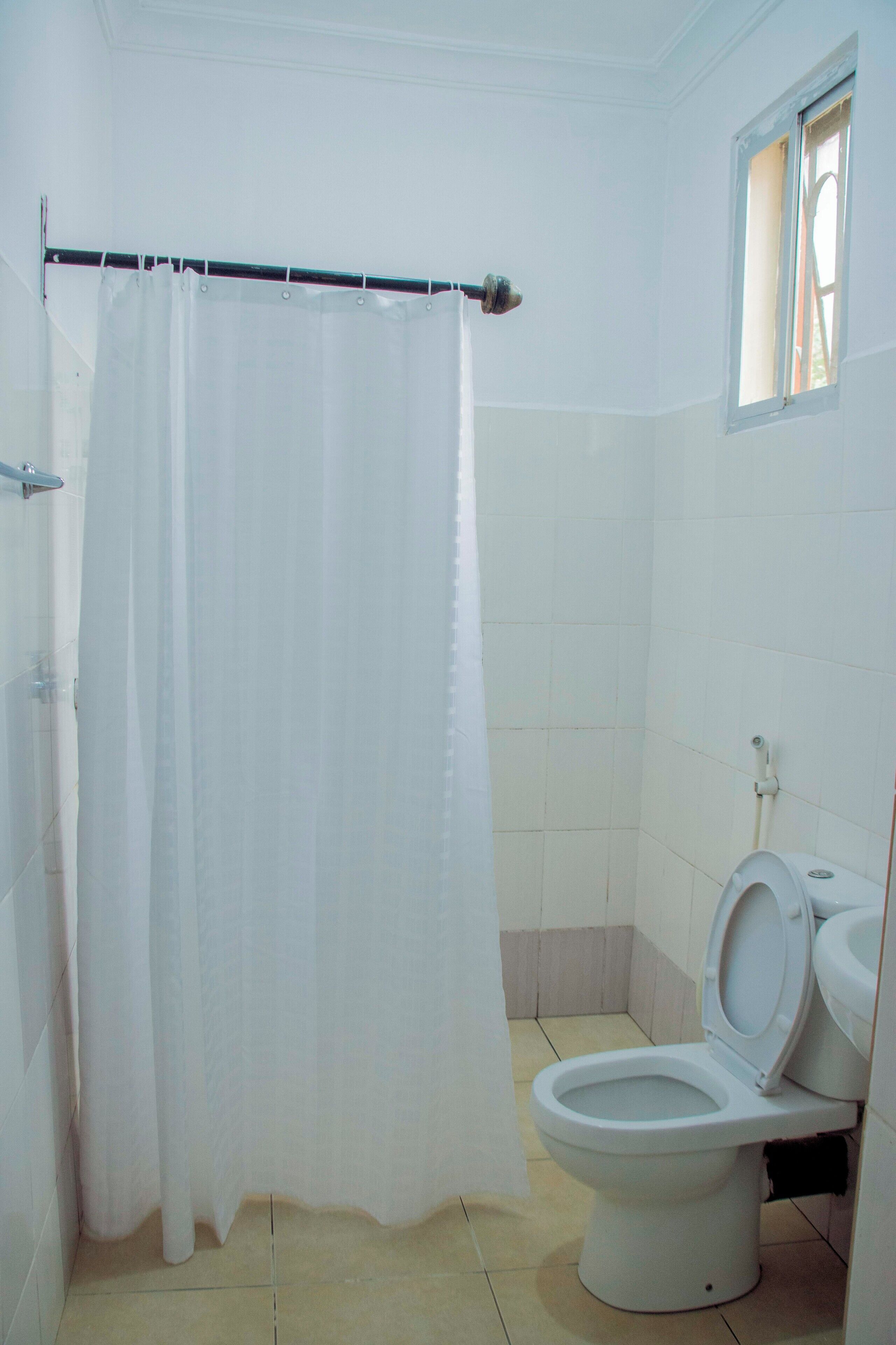 A bathroom with a white toilet, a shower curtain, and tiled walls.