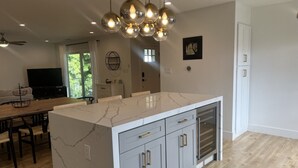 A modern kitchen with a marble island, grey cabinets, and pendant lighting. - Contemporary Home In The Ventura Keys (Ventura)