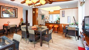 A modern kitchen with wooden beams, a dining area with wicker chairs, and a bar with stools. - Happiness Garden (Ji'an)