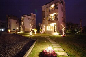 A multi-story residential building with illuminated entryways and a well-maintained lawn. - Happiness Garden (Ji'an)