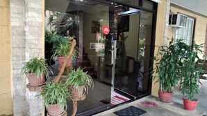 A storefront with a glass door, potted plants, and a metal sign. - La Gracia Apartelle Tagaytay (Tagaytay)