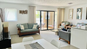 A spacious living area with a sofa, a dining table, and a kitchen area. - Kingscliff Waterfront - large pool, direct creek access & 5 mins walk to beach (Kingscliff)