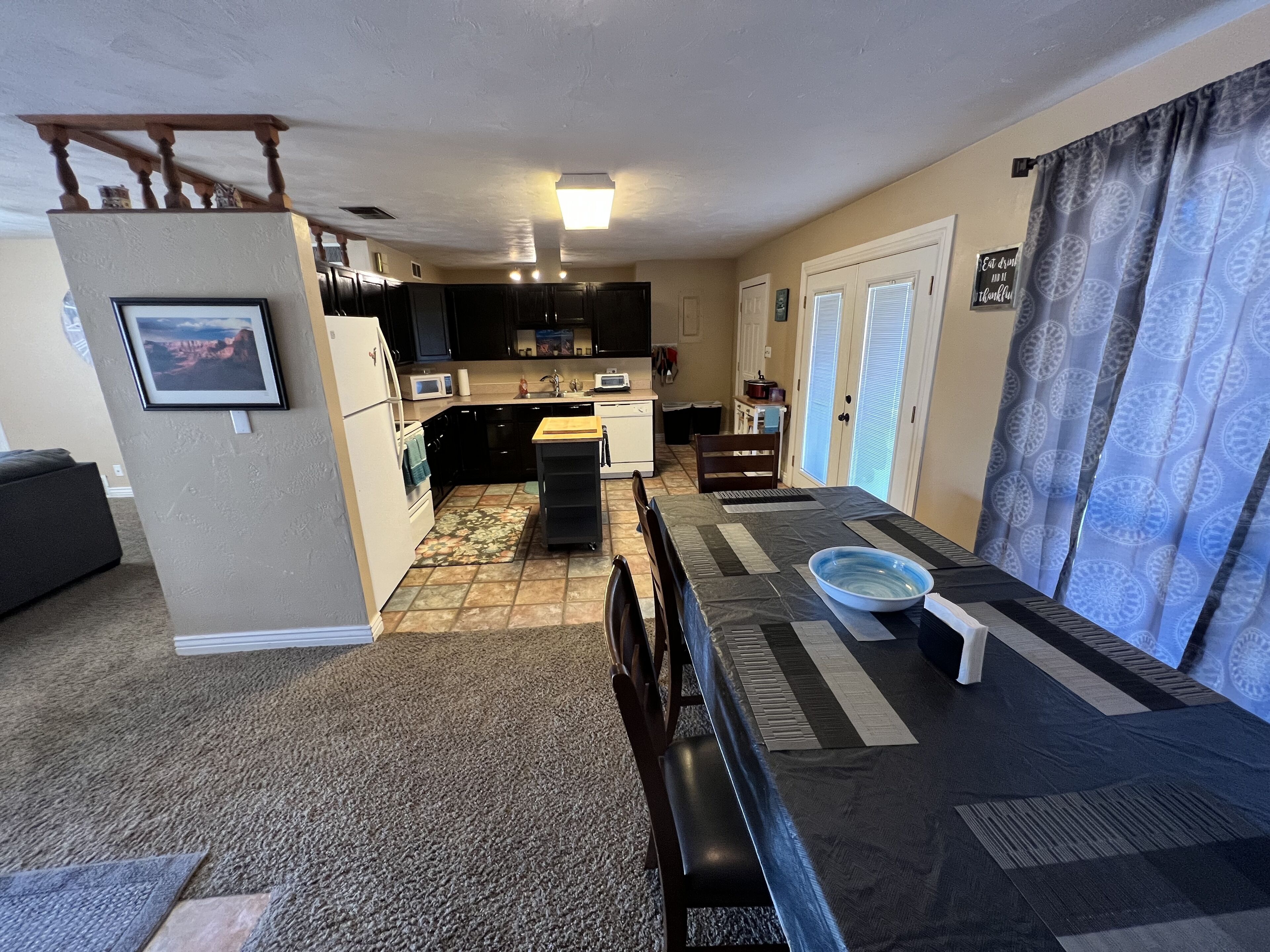 A compact kitchen with dark cabinets, a microwave, and a small dining area with a table and chairs.