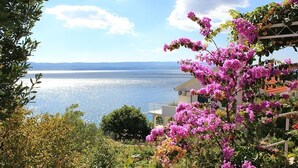 Küstensicht mit blauem Himmel, einem Gewässer und einem Gebäude mit Balkon mit Meerblick.