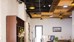A modern interior with wooden tables and benches, a reception desk, and a white brick wall. - Aroma Ha Long Hostel (Bai Chay)